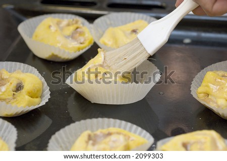 Brushing the saffron buns before the go into the oven