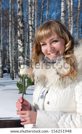 Pretty smiled young woman with white rose in winter nature