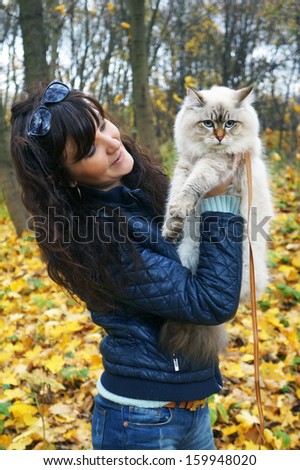 Siberian cat and young woman in a autumn forest