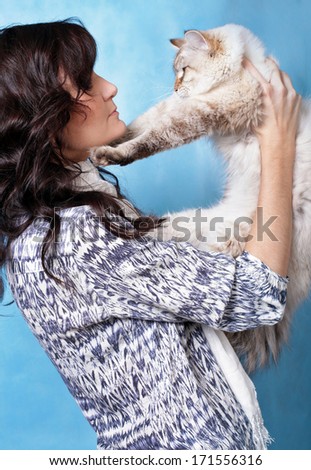 Charming young woman with Siberian cat on blue background