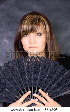 Charming young woman with  fan. Fashion studio portrait