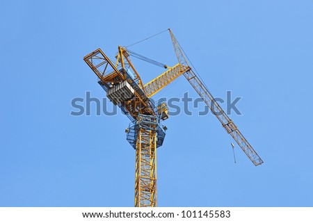 Yellow construction tower crane against blue sky