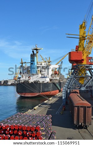 Pipe stack, ship ans train under crane bridge