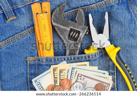 Earnings concept - money and tool in blue jeans pocket