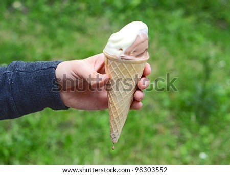 Ice cream in hand on natural green background
