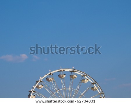 Ferris Wheel Title Image. The Ferris Wheel is against a blue sky with a few white clouds. There is plenty of room at the top for copy.