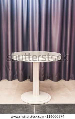 white round table on the background of purple curtains
