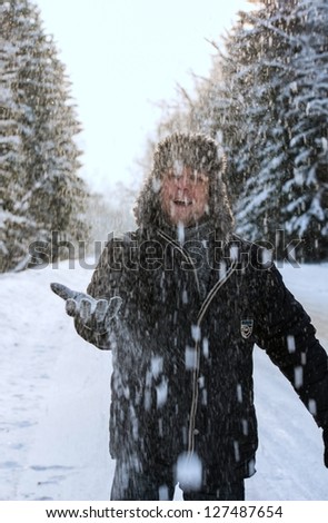 A young man throws up snow in the forest