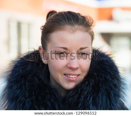 Portrait of a young girl in a fur collar sunlit
