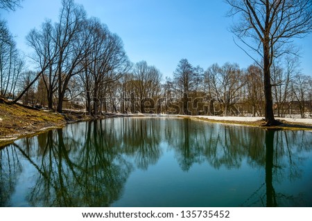 clear pond in the park with orazheniem sky in early spring