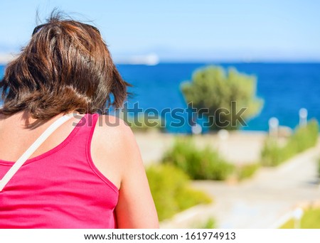 woman standing alone on the balcony and looking at the sea