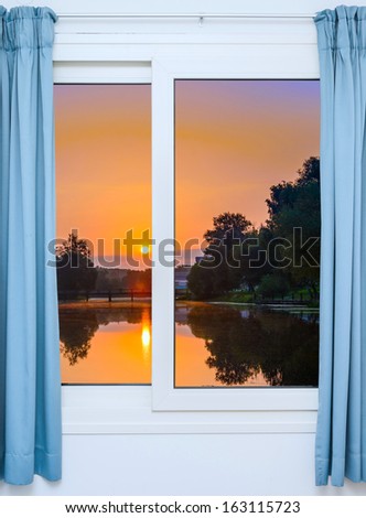 view from the window with the curtains of the sunset over the water
