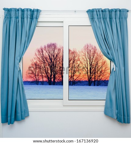 view from the window with the curtains of the sunset over the snow