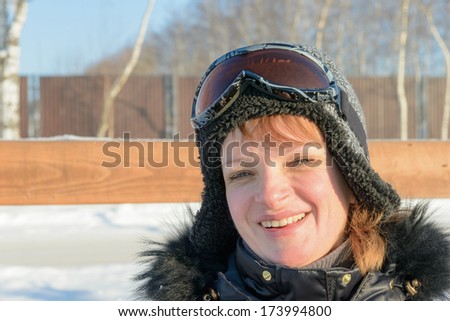 brunette woman on a hillside in a cap and ski goggles