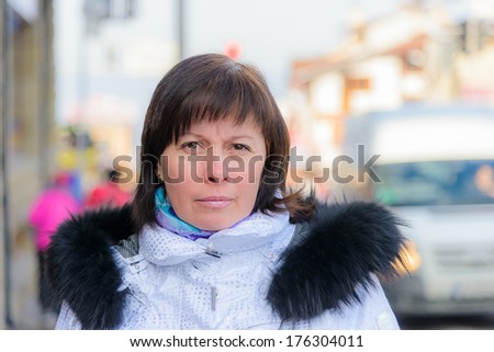 Brunette middle-aged woman in a stylish white jacket with a fur collar