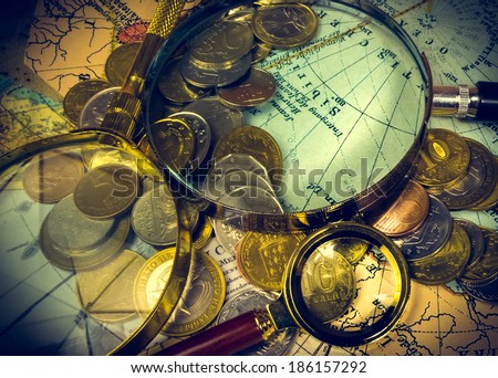 compass and magnifying glass gold color on the old map with coins