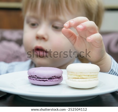 little blond boy sitting at a table eating cake
