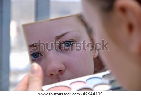 The girl does make up before mirror