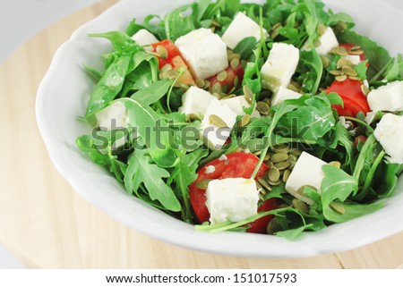 Salad with arugula, tomatoes, goat cheese and pumpkin seeds