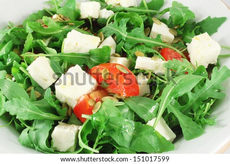 Salad with arugula, tomatoes, goat cheese and pumpkin seeds