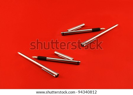 A set of writing pens on a red background