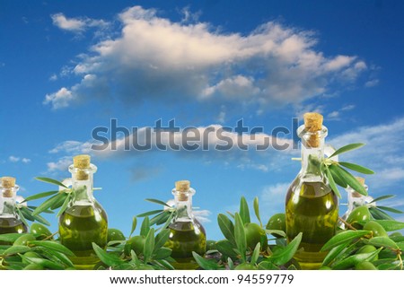 Olive oil bottles and olives against a sky