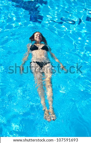 Top view of young woman swimming underwater in the pool