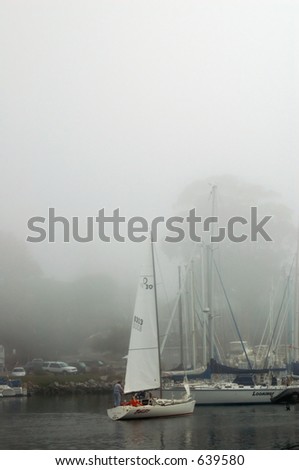 A sailboat gets underway on a foggy morning in Santa Cruz, California