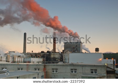 Factory belching out smog from its smokestacks lit by the evening light