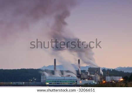 Factory belching out smog from its smokestacks lit by the evening light