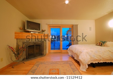 interior bedroom of an upscale house with fireplace and tv stand