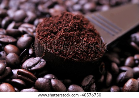 coffee grounds on a scooper on a pile of coffee beans