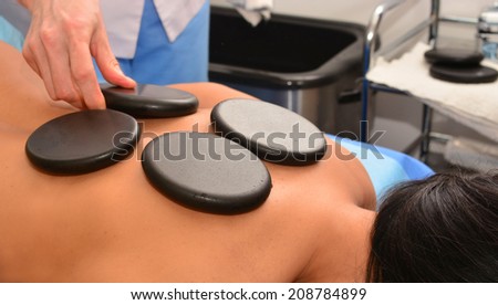 Stone therapy, stone massage, spa, woman doctor puts hot stones on the patient\'s back