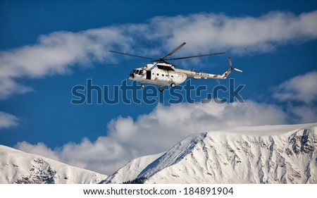 helicopter flying on the background of snow-capped peaks of the mountains
