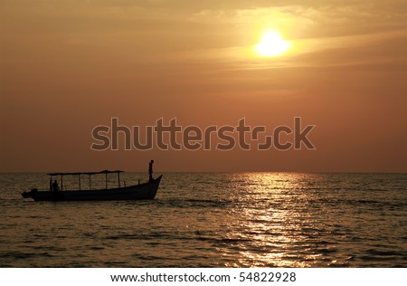 Fishing boat silhouetted against the setting sun in a tropical location.