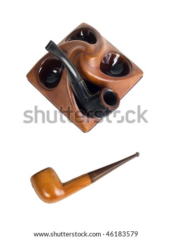two leather bound tobacco pipes, one laying on it\'s side other standing in a pipe stand. isolated on white