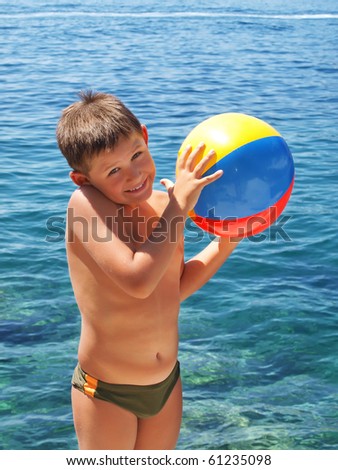 Little boy holding a colorful beach ball by the ocean