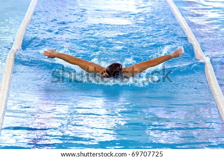 Olympic swimmer during butterfly stroke training in indoor swimming pool.