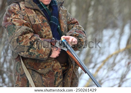 Close-up of a hunter loading his old russian double-barreled side by side shotgun in winter forest