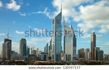 Panorama of tall Skyscrapers in skyline of Dubai against blue sky.