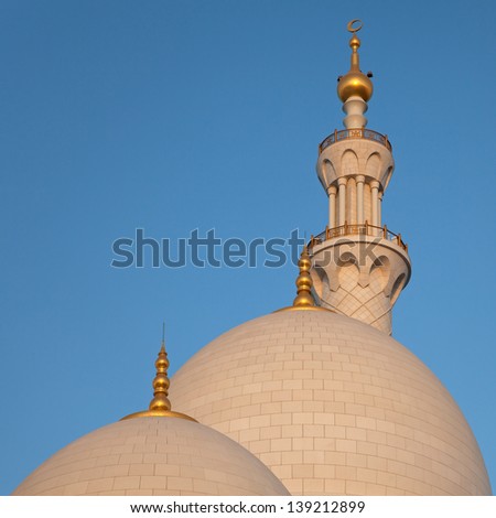 Two Domes and One Minaret of Abu Dhabi Sheikh Zayed Mosque against blue sky.