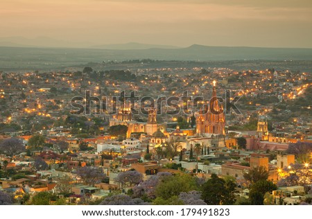 Illuminated skyline of San Miguel de Allende in Mexico after sunset, with a yellow filter effect.