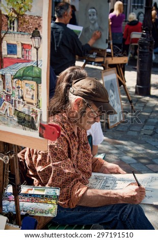 PARIS, FRANCE - JUNE 07, 2010: Artist at Work in Place du Tertre of Montmartre, which is a cafe-lined cobbled square and a hangout for buskers and artists painting landscapes and tourist portraits.