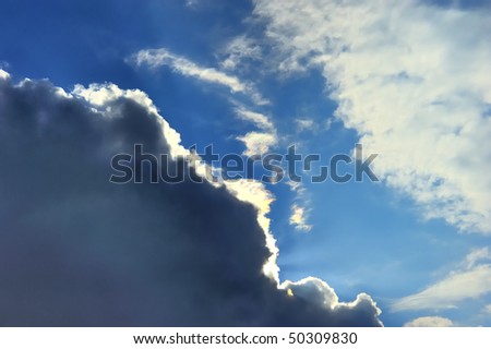 sun covered by pretty clouds in clear blue sky, projecting remarkable colorful beams
