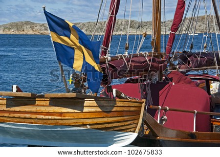 Tall ship with wooden lifeboat and a Swedish flag.