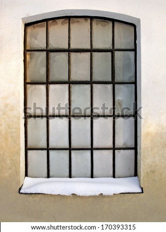 Old checkered window with small panes frosty in winter.
