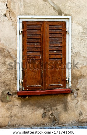 Wall with window and brown window shutter in Switzerland.