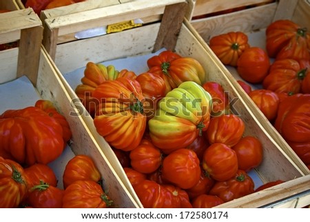 Home grown red beefsteak tomatoes in wooden boxes for sale at farmers market.
