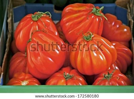 Carton with big red beefsteak tomatoes for sale.