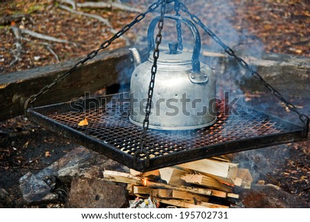 Cooking coffee in old time coffee pot over fire in the forest in fall.